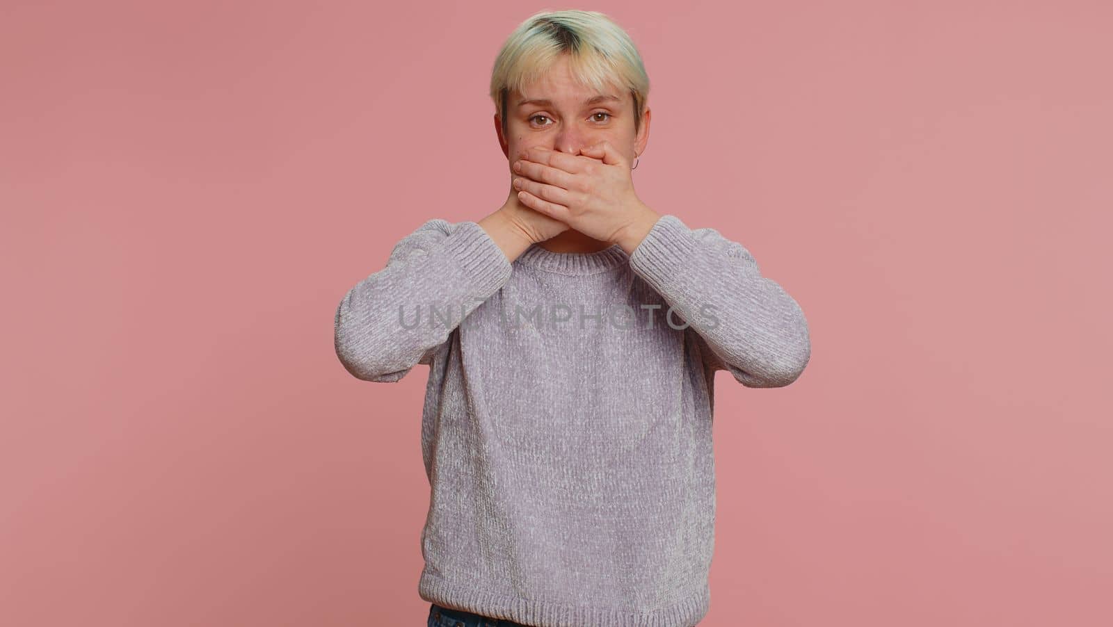 I will not say anyone. Frightened sincere woman closing her mouth with hand, looking intimidated scared at camera, gestures no, refusing to tell terrible secret, unbelievable truth. Afraid lgbt girl