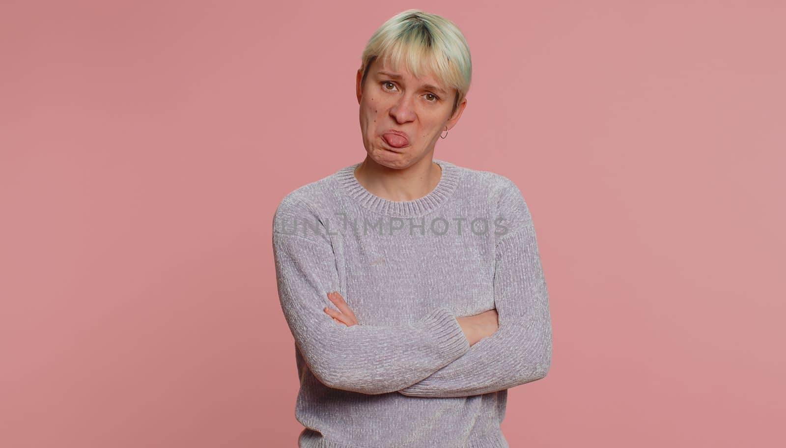 Offended millennial woman with short green hair having misunderstanding frustrated after quarrel, ignores and does not want to communicate, talk. Young girl on pink background. Lgbt gay lesbian people