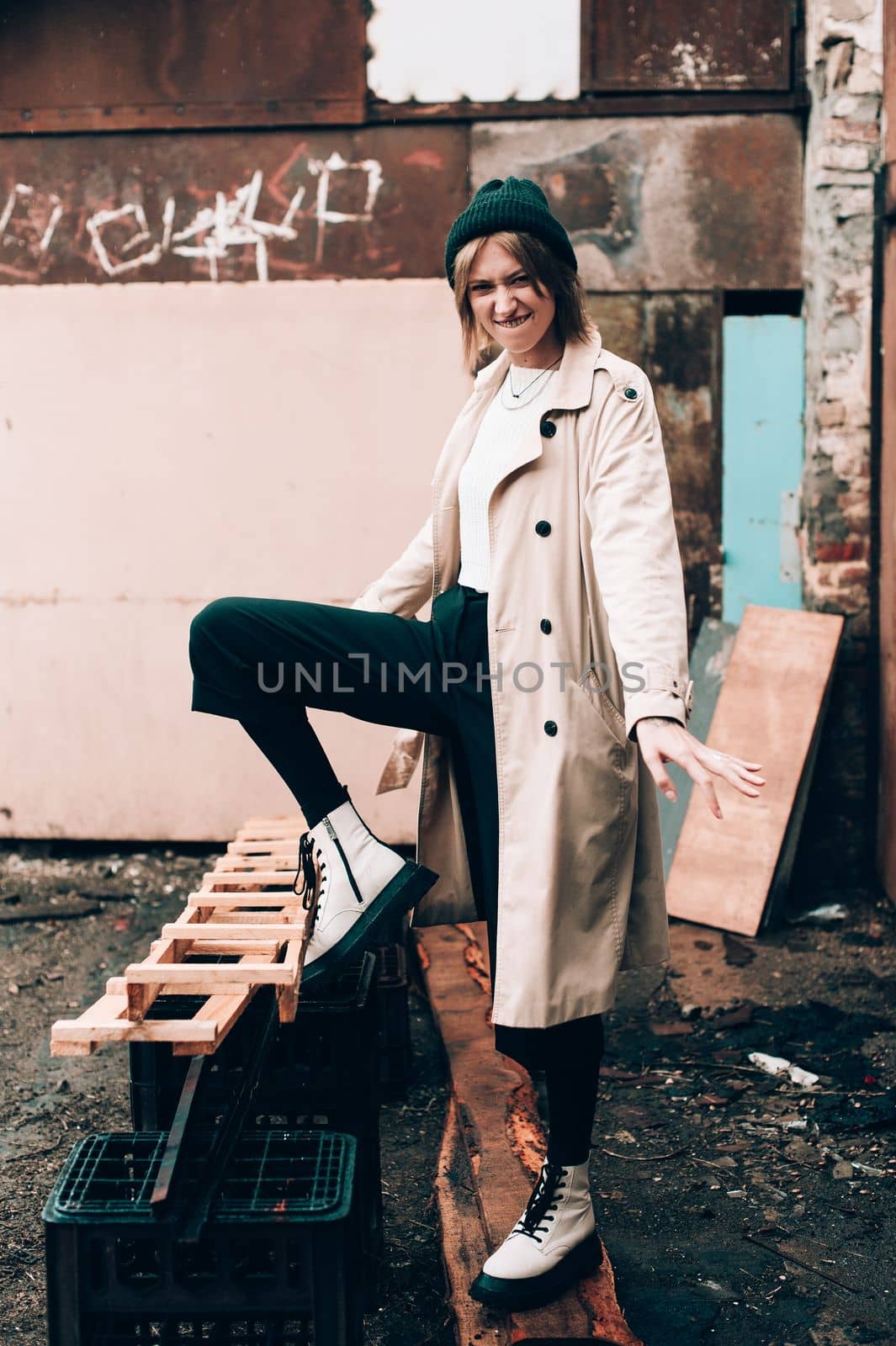 Beautiful young stylish blonde woman wearing long beige coat, white boots, black hat posing through the city streets. Trendy casual outfit. Selective focus, grain by Ashtray25