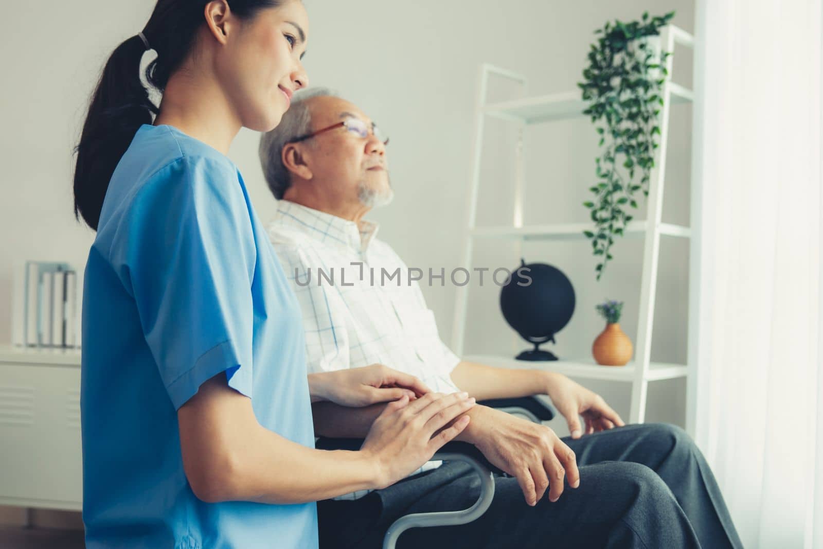 Caring nurse and a contented senior man in a wheel chair at home, nursing house. Medical for elderly patient, home care for pensioners.