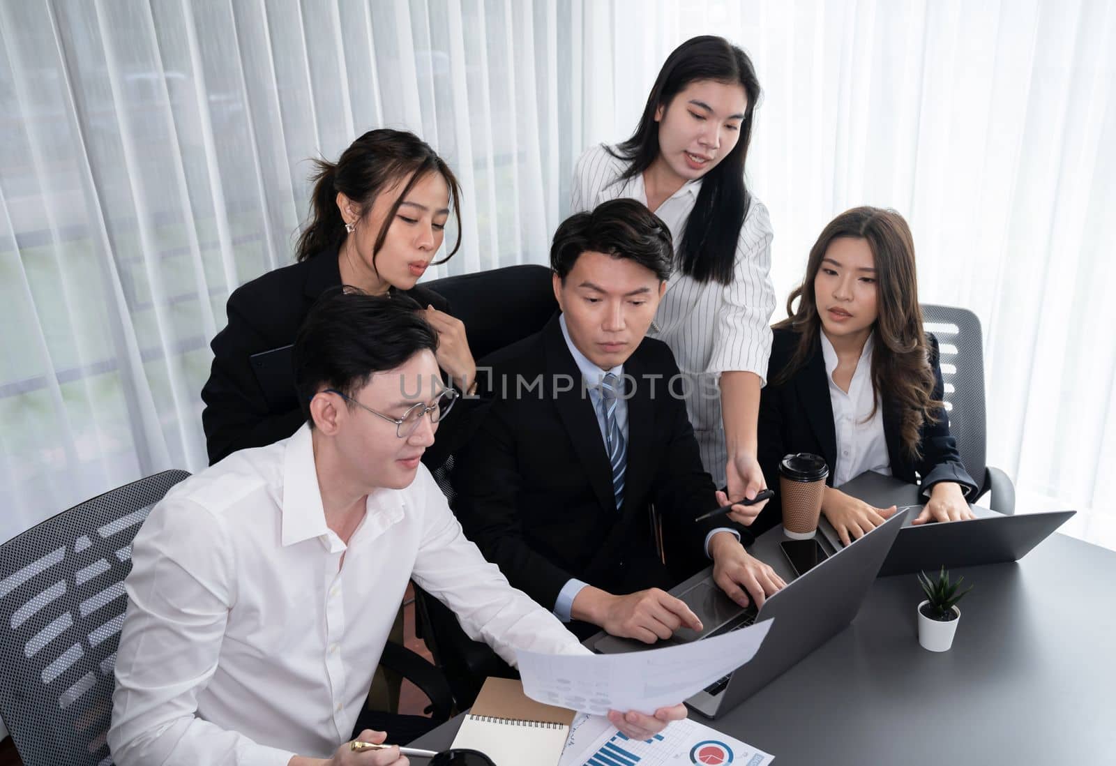 Harmony in office concept as business people analyzing dashboard paper together in workplace. Young colleagues give ideas at manager desk for discussion or strategy planning about project.