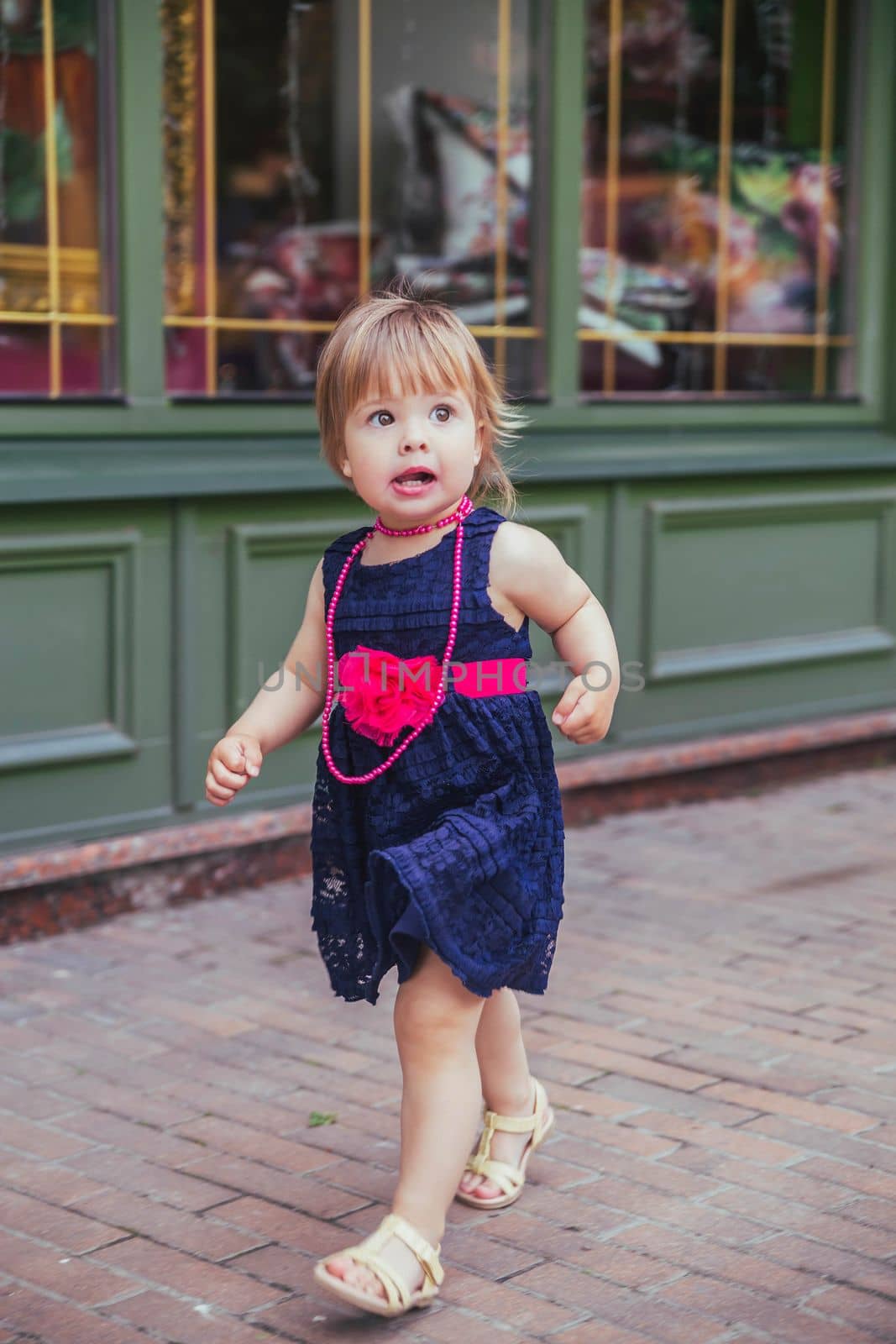 beautiful baby girl in dress running down the street.