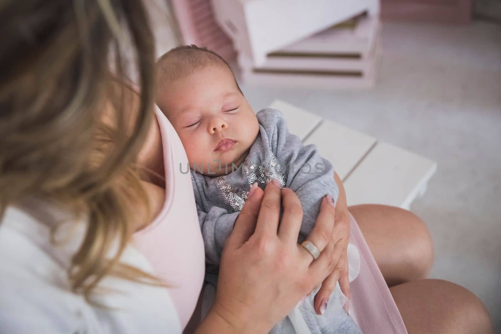 mother holds the sleeping charming newborn daughter.