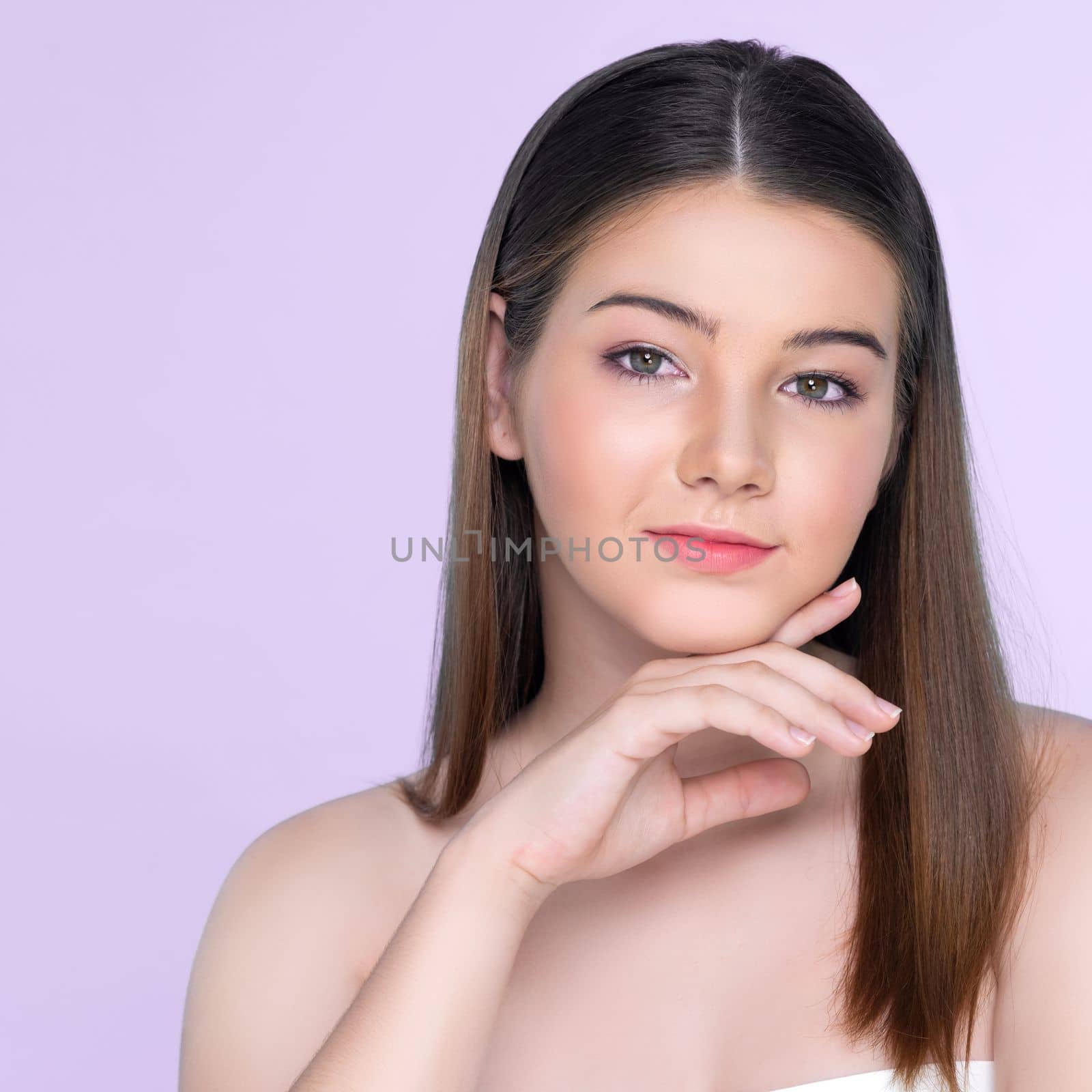 Portrait of young brunette with long hair and flawless skin with hand gesture for beauty and cosmetic concept. charming beautiful young girl posing hands for skincare or cosmetic advertising.