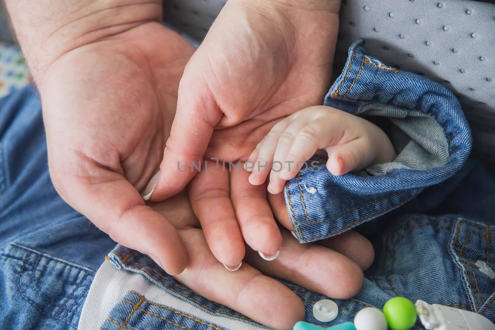 married couple holding the hand of their newborn baby.