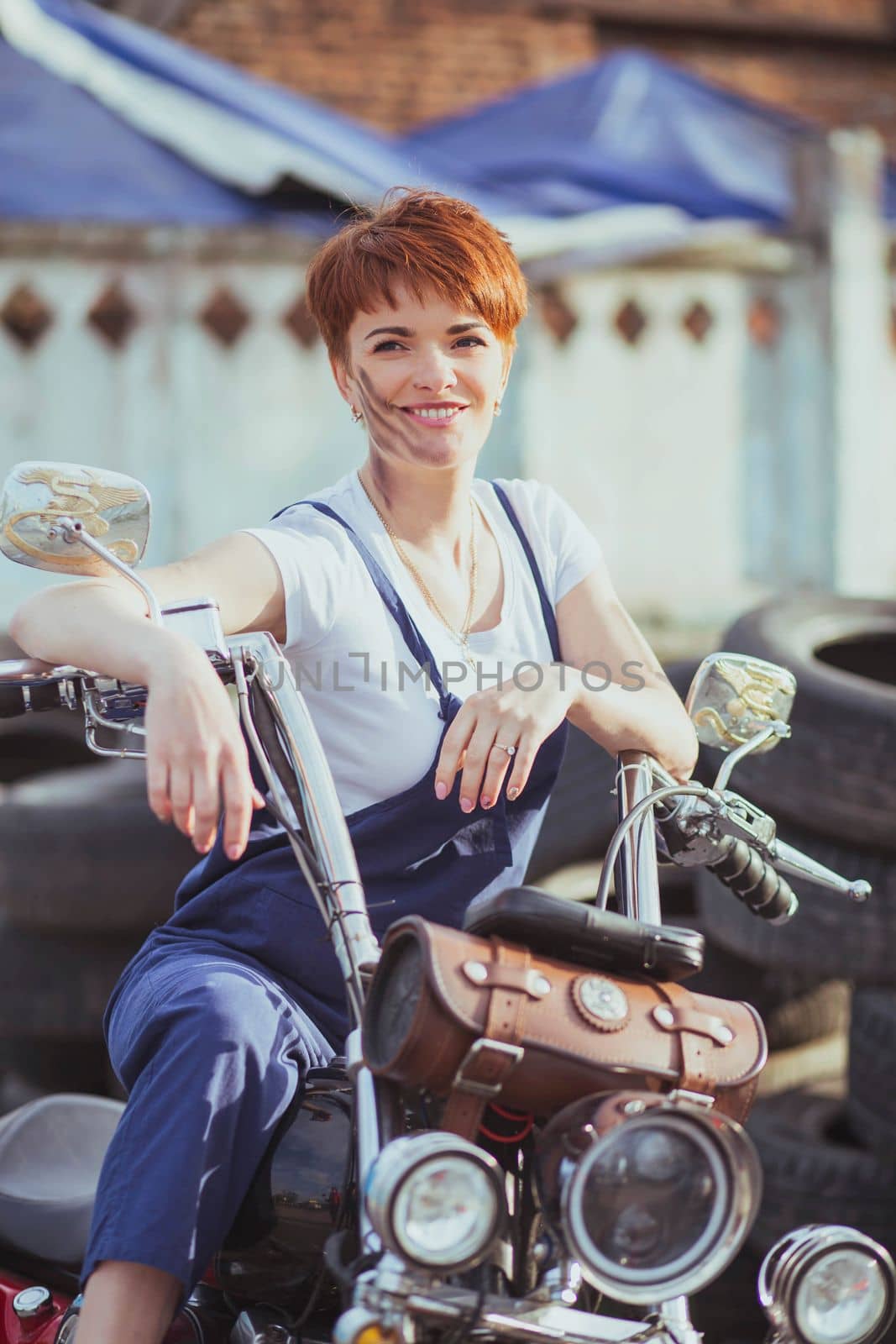 Girl auto mechanic smiling on a motorcycle.