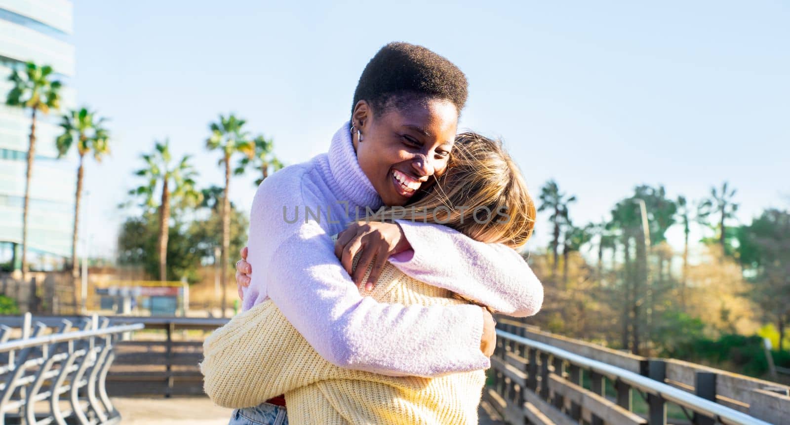 Two girls friends hugging affectionately happy smiling. Women having fun together and embracing. by PaulCarr