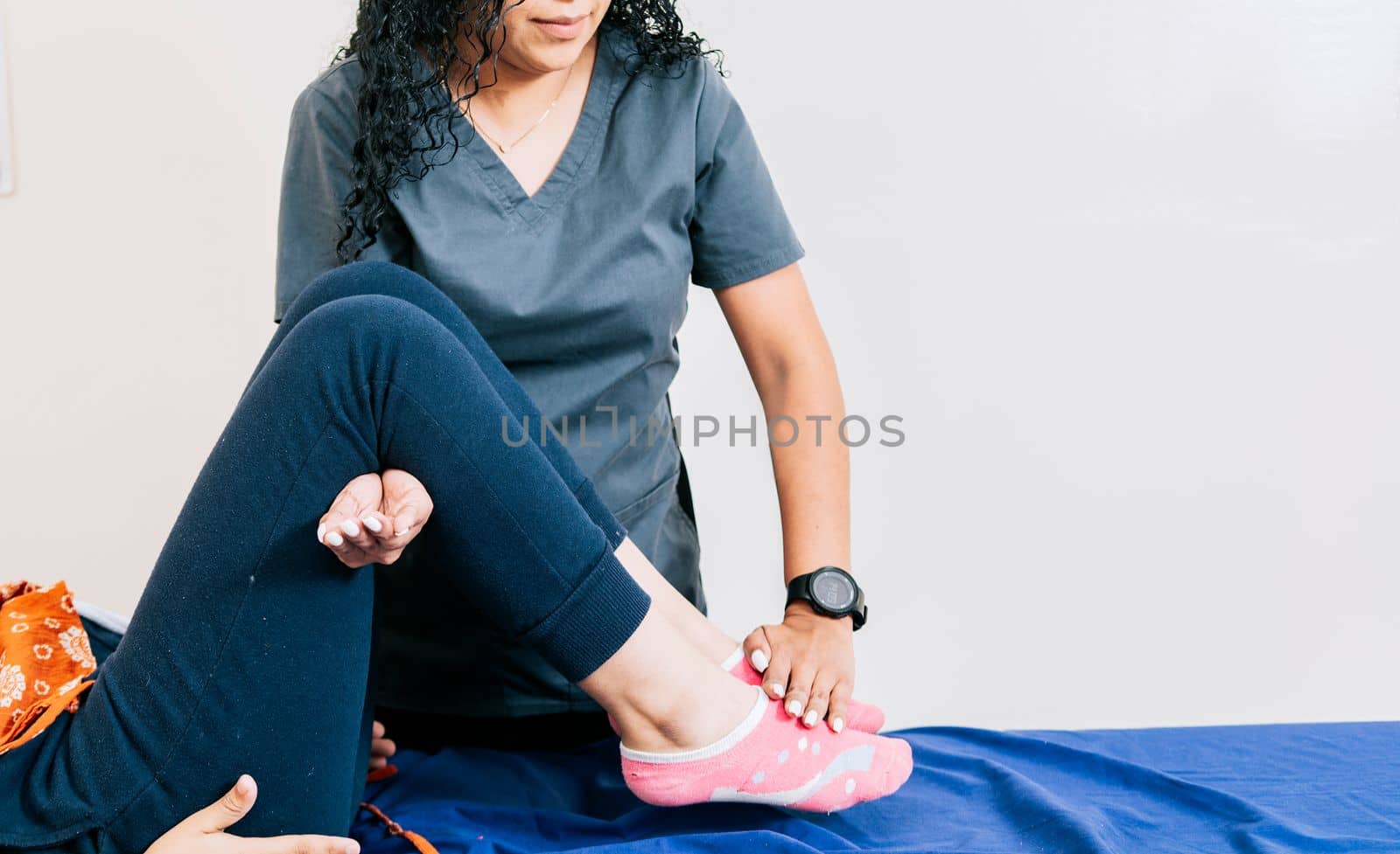 Professional physiotherapist assisting patient in leg rehabilitation, Modern leg rehabilitation physiotherapy, Worker in modern physiotherapy assisting female patient
