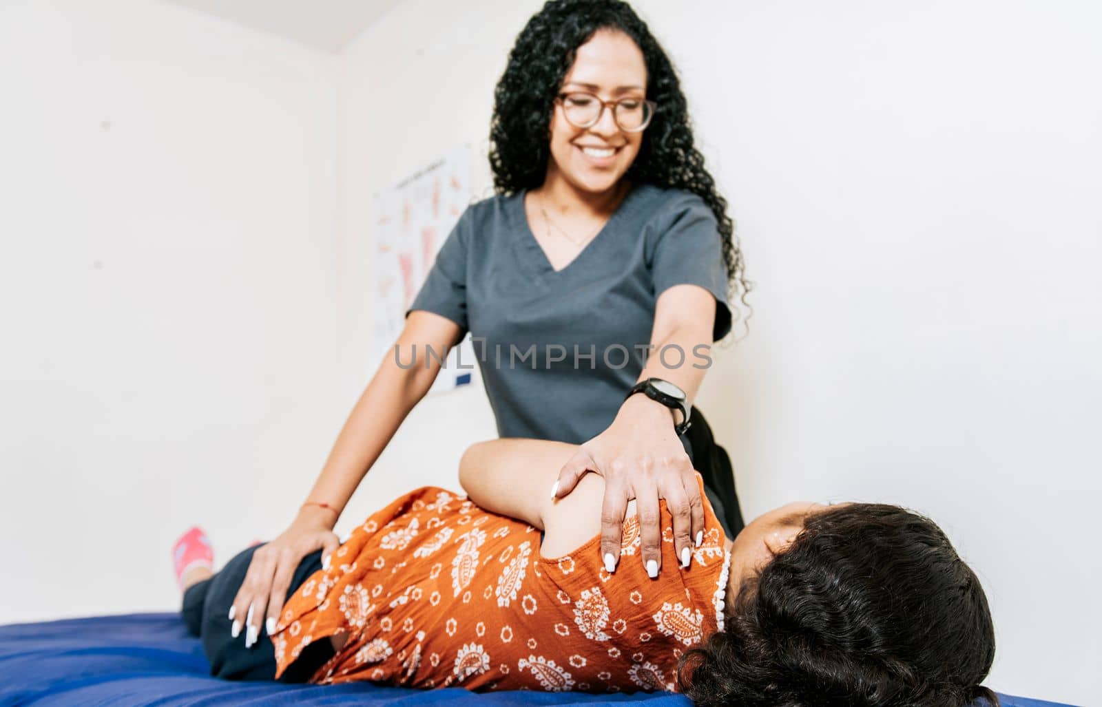 Woman doing shoulder rehabilitation physiotherapy. Physiotherapist rehabilitating shoulder to patient lying on her side. Shoulder and back treatment and rehabilitation concept by isaiphoto
