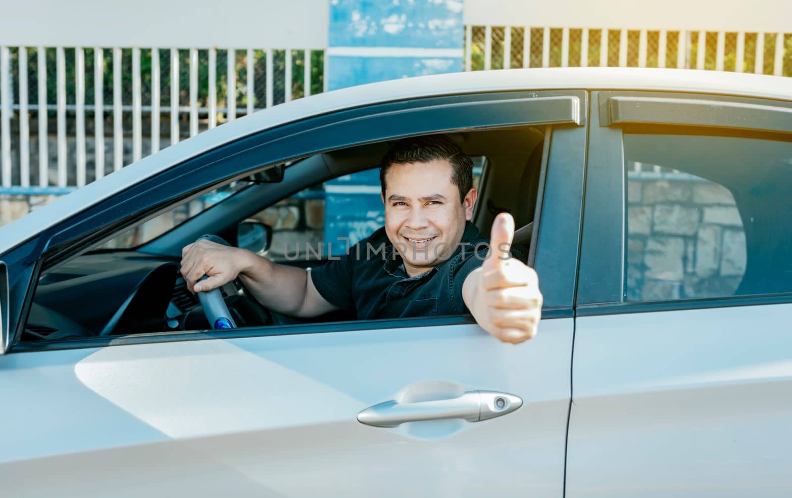 Satisfied driver man showing thumb up. Young driver man in the car showing thumb up. Happy driver giving a thumbs up on the road. safe driving concept