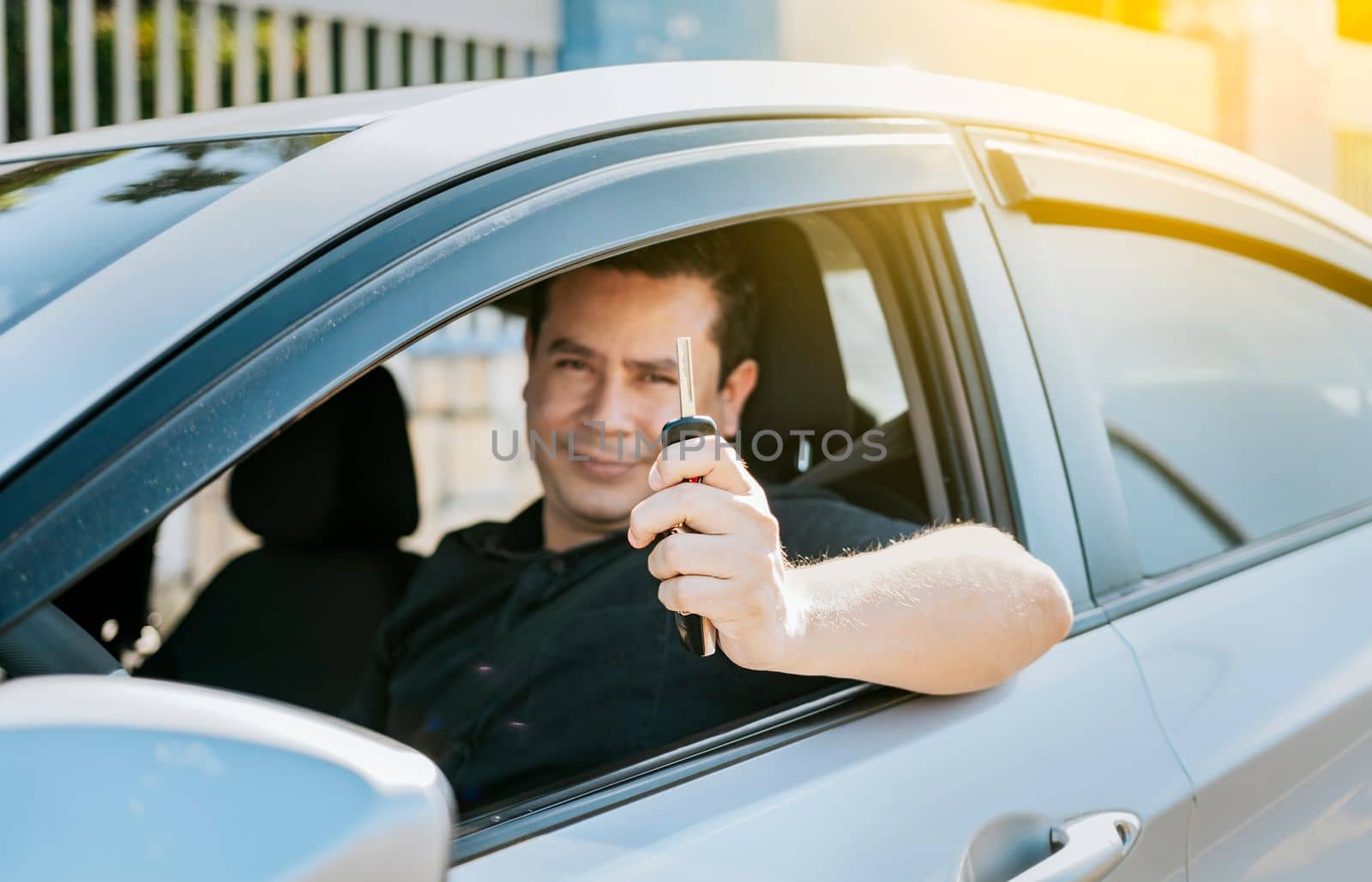 Happy man showing his new car keys, Person in his vehicle showing his car keys, Satisfied car buyer concept, Driver in his car showing the keys out the window