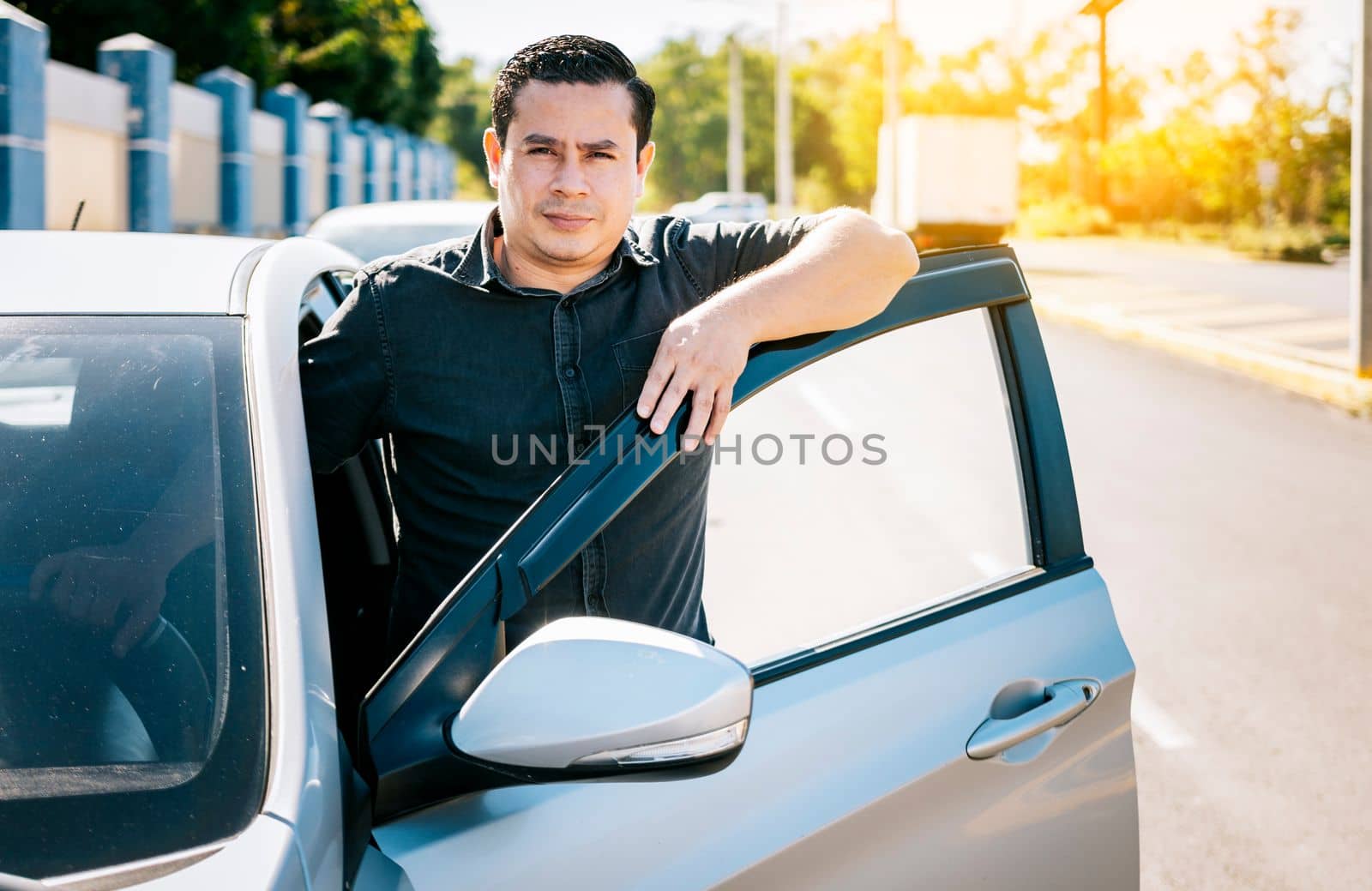 Close up of driver leaning on the car door in the street, Young latin man leaning on car door in the street. Smiling driver leaning on the car door. Smiling owner with new car