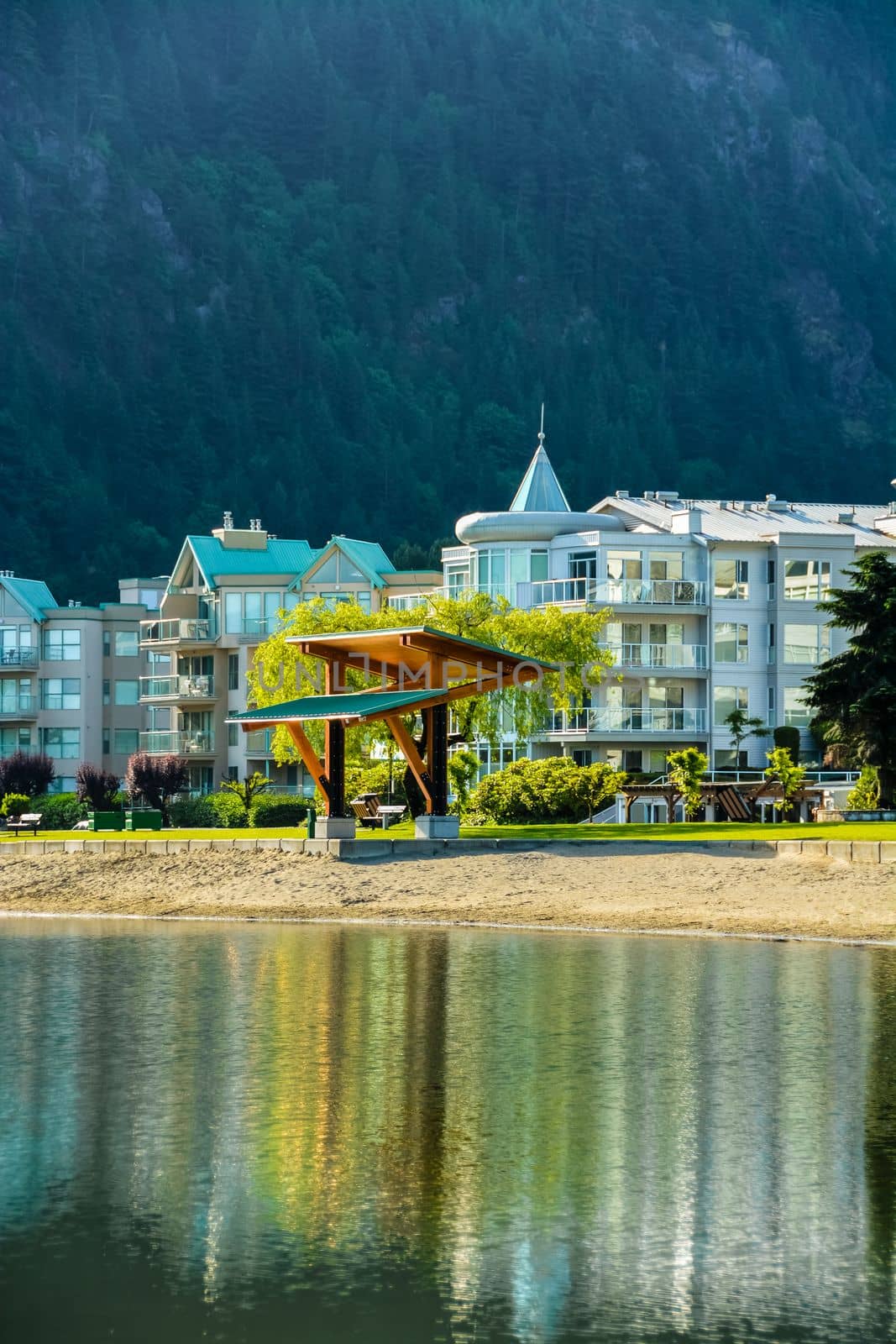 Resort buildings at waterfront on mounting forest background.