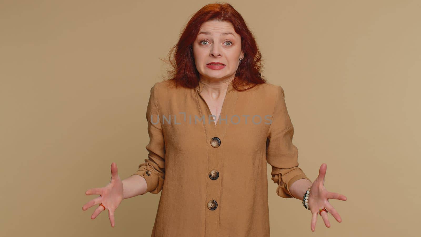 Woman in blouse screams yell from stress tension problems feels horror hopelessness fear panic surprise shock expresses gestures rage. Young pretty redhead girl isolated on beige studio background