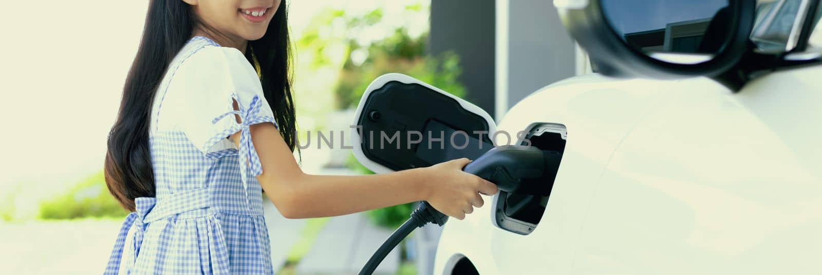Sustainable power source for progressive lifestyle shown by a girl hold EV plug by biancoblue