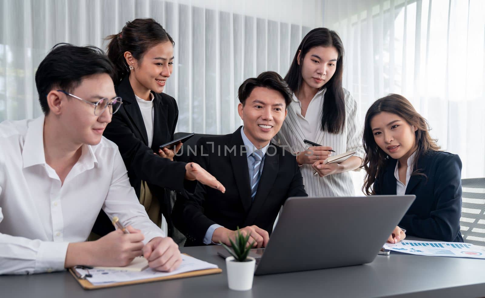 Harmony in office concept as business people analyzing dashboard paper together in workplace. Young colleagues give ideas at manager desk for discussion or strategy planning about project.
