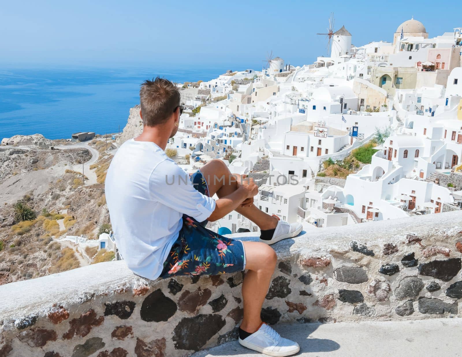 young men at Oia Santorini Greece on a sunny day during summer with whitewashed homes and churches, Greek Island Aegean Cyclades