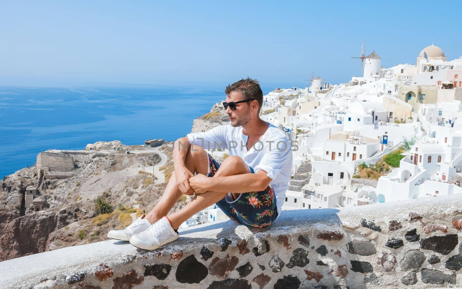 Young men at Oia Santorini Greece on a sunny day during summer with whitewashed homes and churches by fokkebok