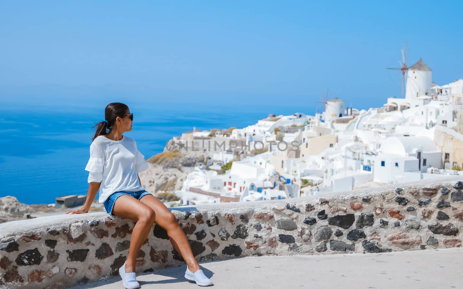 Asian woman visit Oia Santorini Greece on a sunny day during summer with whitewashed homes and churches, Greek Island Aegean Cyclades