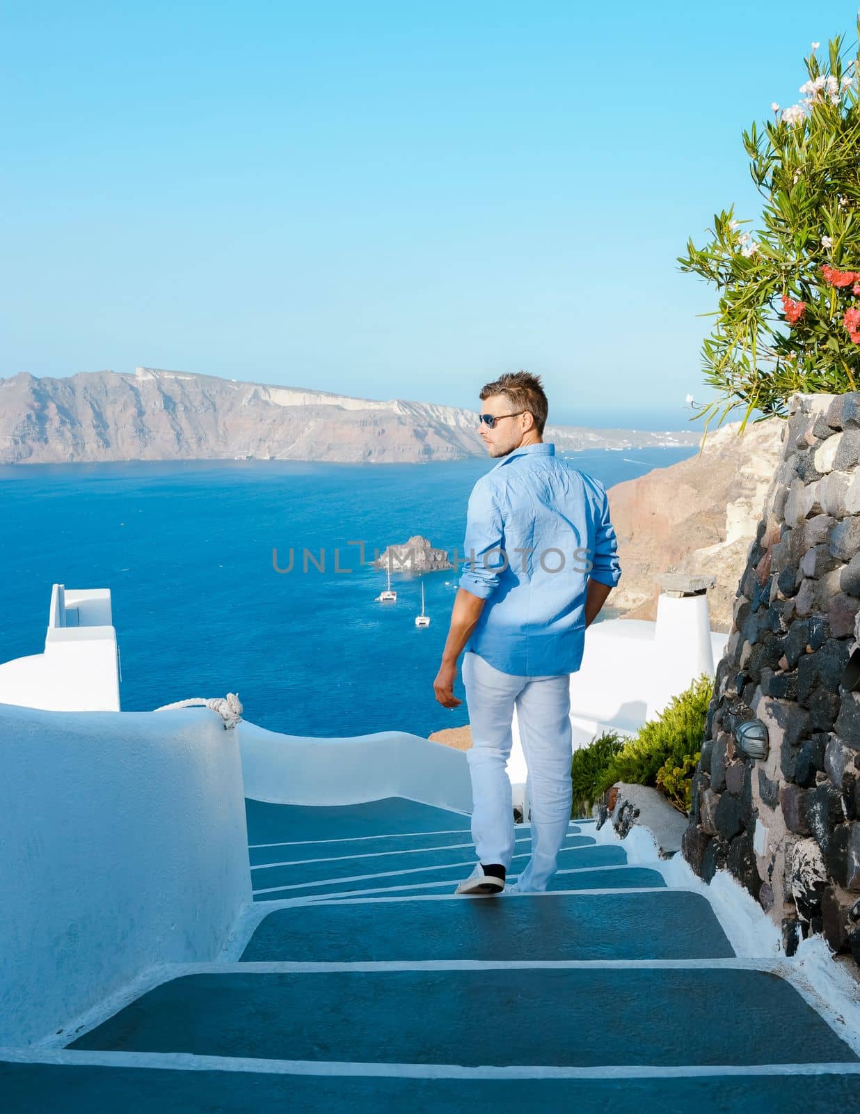 Young men tourist visit Oia Santorini Greece during summer with whitewashed homes and churches by fokkebok