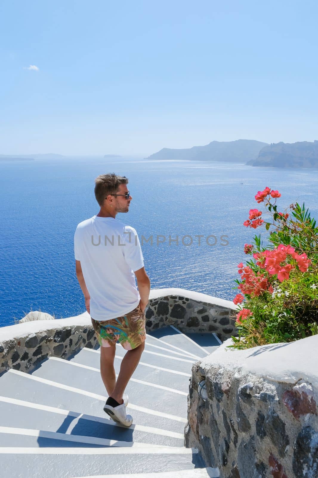 Young men tourists visit Oia Santorini Greece on a sunny day during summer with whitewashed homes and churches, Greek Island Aegean Cyclades