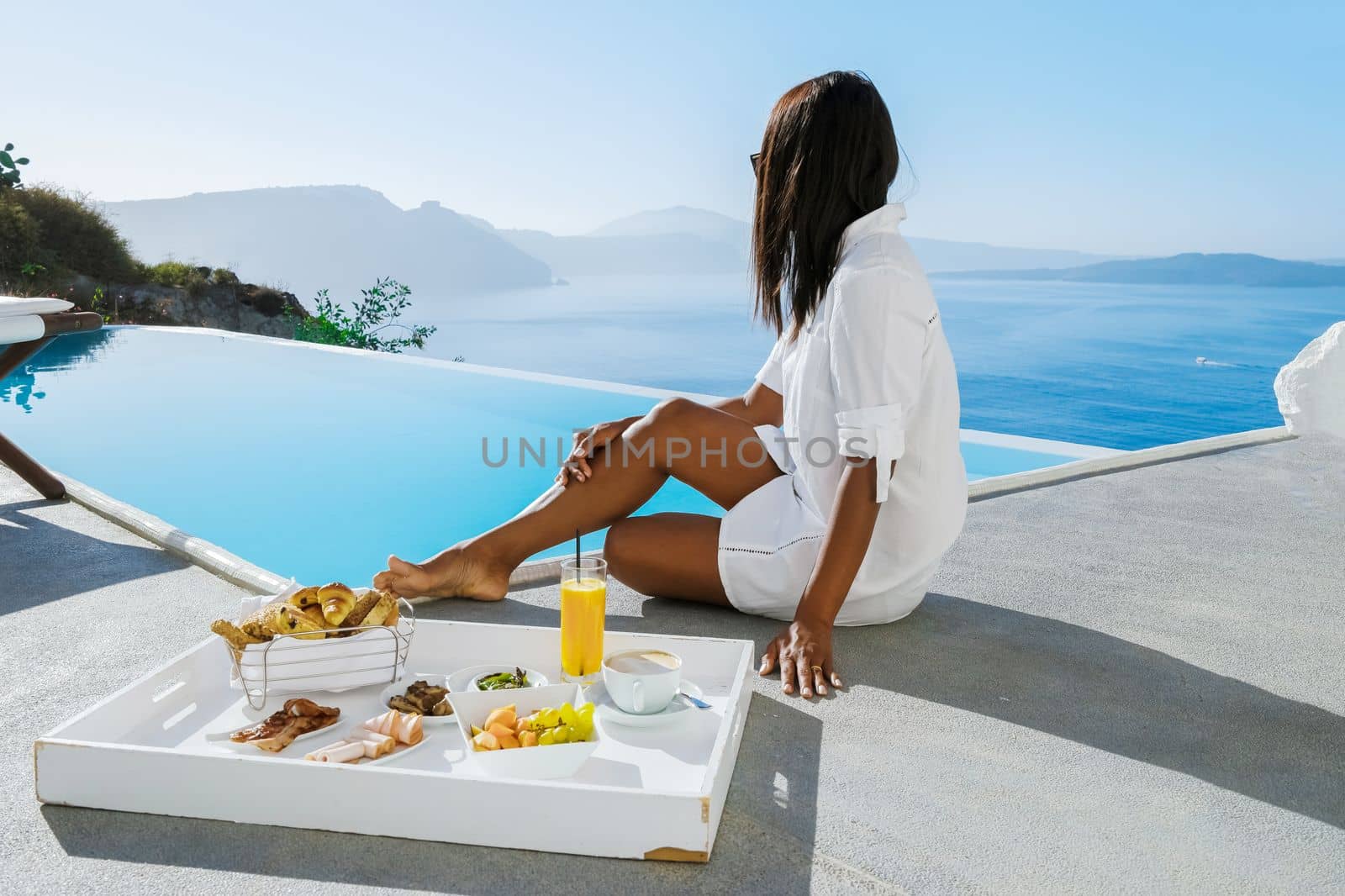 Women having breakfast by the infinity pool looking out over the Caldera ocean of Santorini Greece by fokkebok