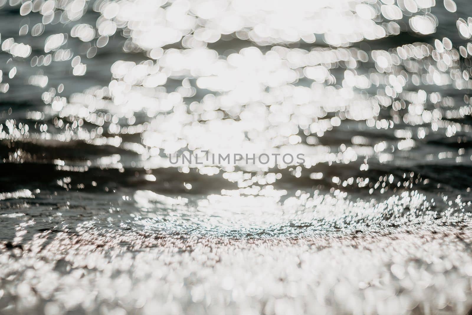 Abstract sea summer ocean sunset nature background. Small waves on golden water surface in motion blur with golden bokeh lights from sun. Holiday, vacation and recreational concept. by panophotograph