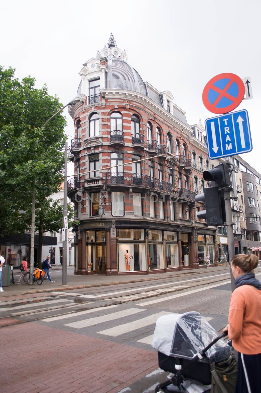 a young mother with a stroller crosses the road at a pedestrian crossing at a green traffic light in city, Antwerp, Belgium, 12 July 2019. High quality photo