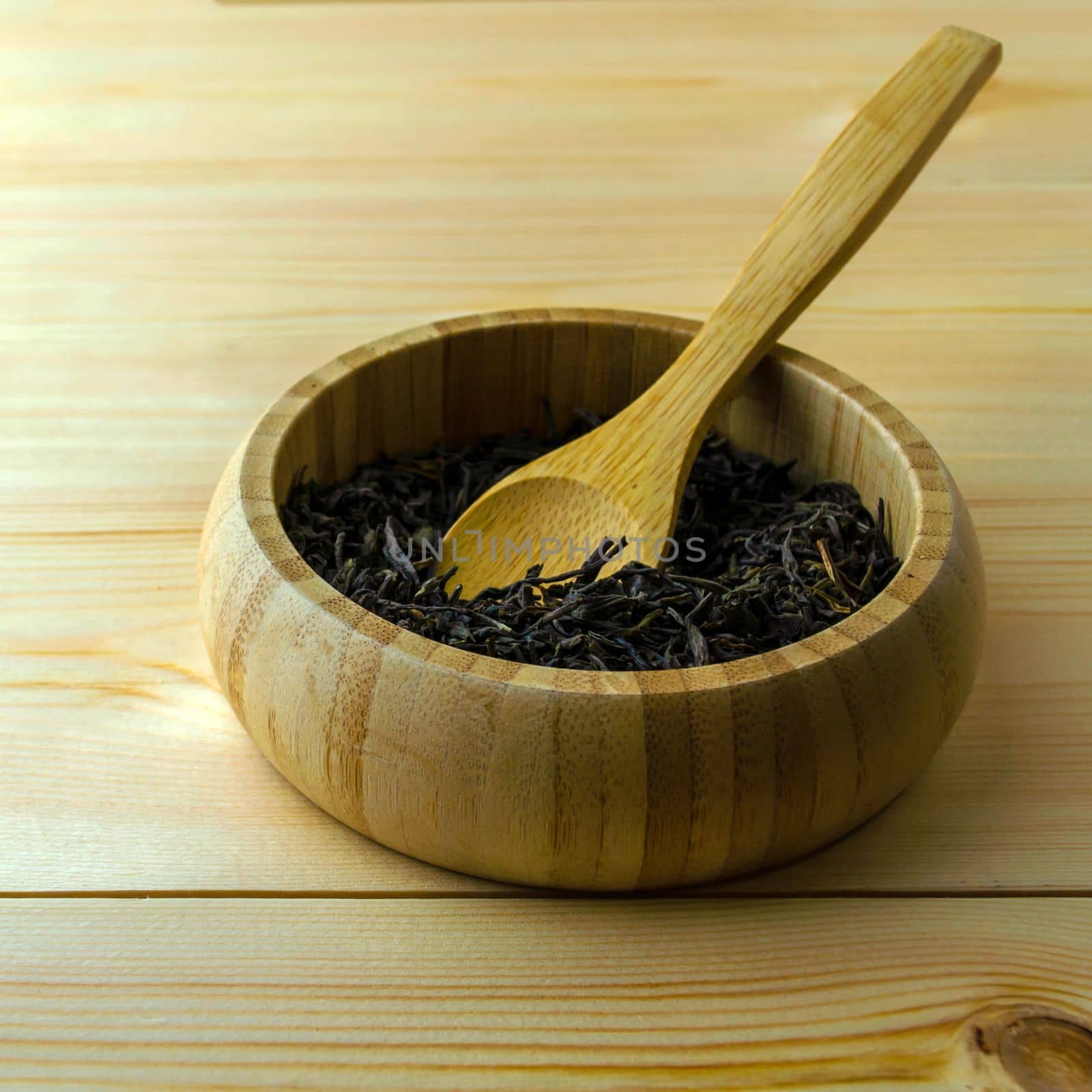 Leaf dry green tea, square photo. Leaf dry green tea in a wooden plate on a wooden table.