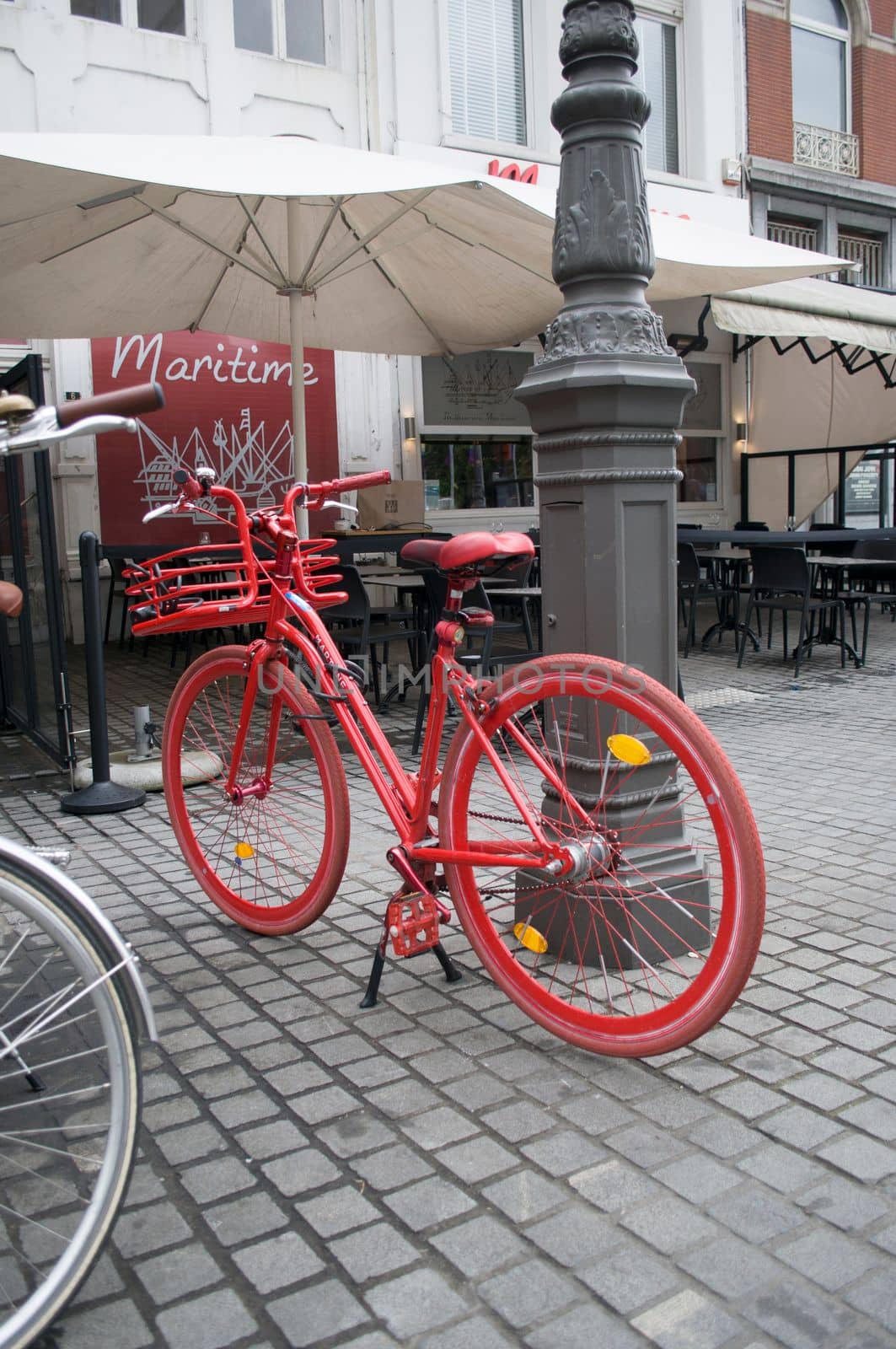 a red-painted bicycle near a pole in front of a street cafe, Antwerp, Belgium, 12 July 2019. High quality photo