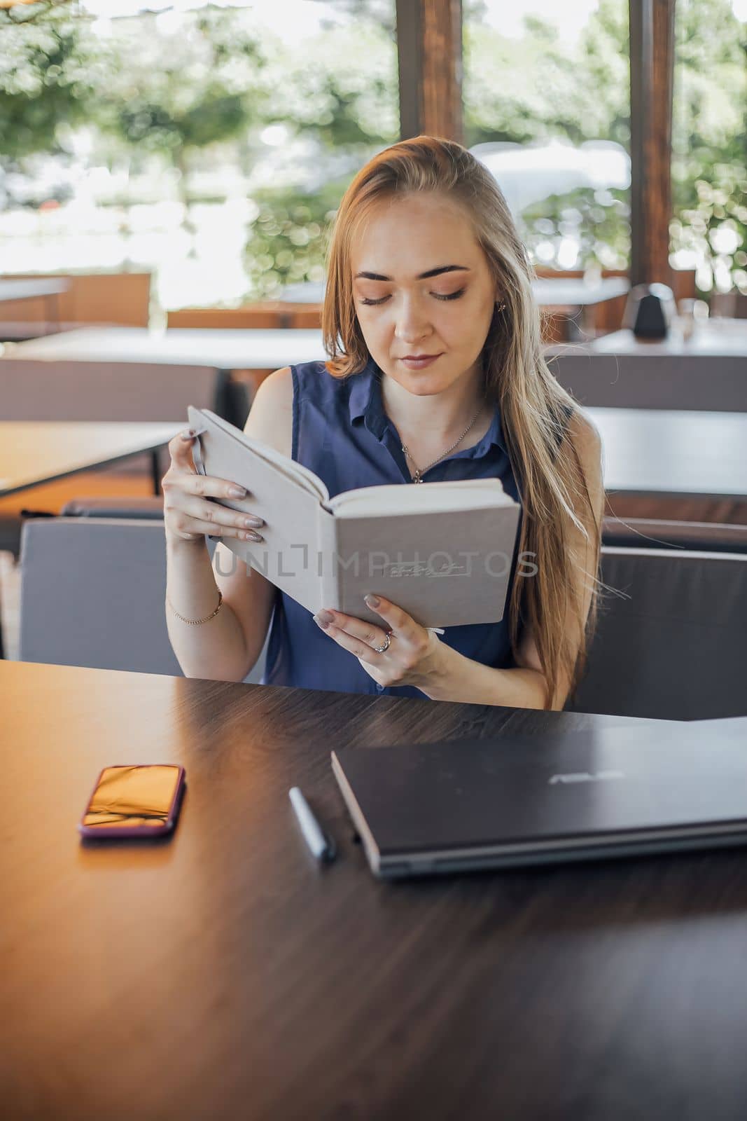 Beautiful woman with short hair sitting at the terrace on a sunny day working from home using laptop