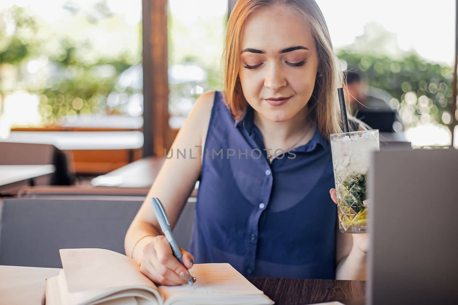 Beautiful woman with short hair sitting at the terrace on a sunny day working from home using laptop