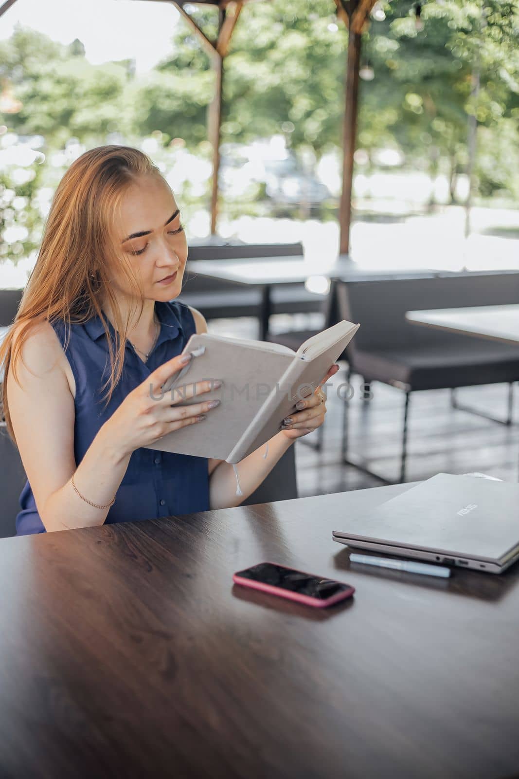 Beautiful woman with short hair sitting at the terrace on a sunny day working from home using laptop