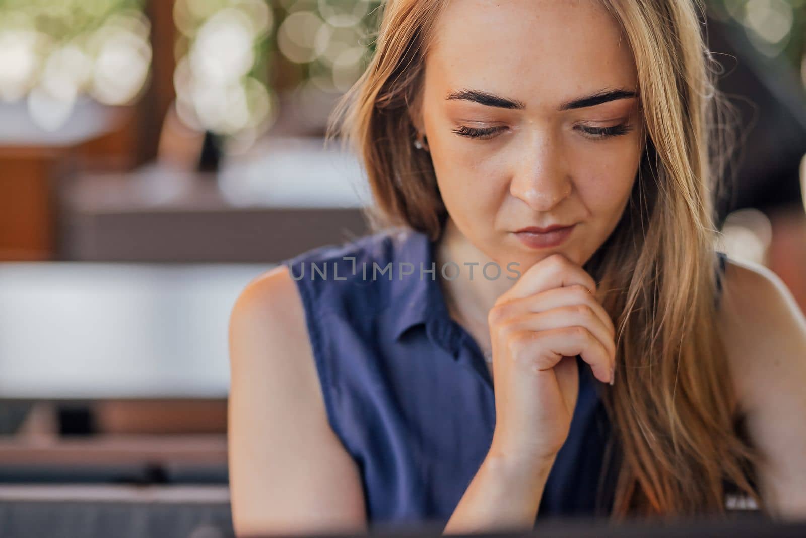 a girl sits on a summer terrace and works at a laptop. freelance. selfeducation. the concept of remote learning and outdoor work