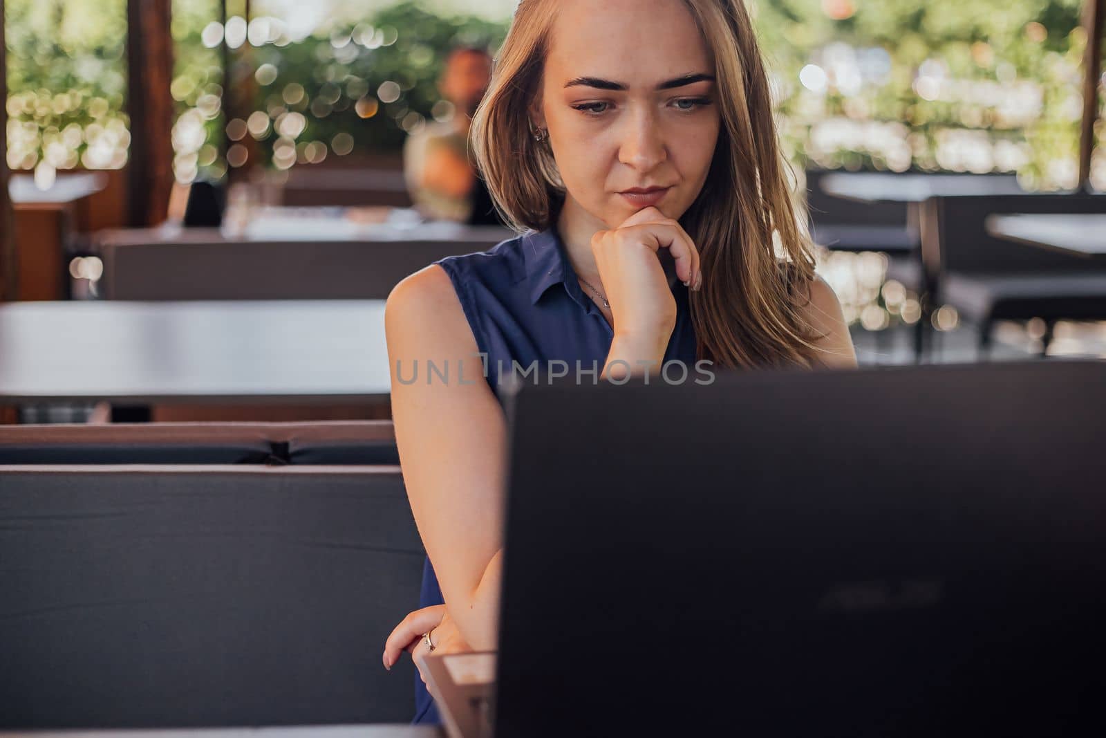a girl sits on a summer terrace and works at a laptop. freelance. selfeducation. the concept of remote learning and outdoor work