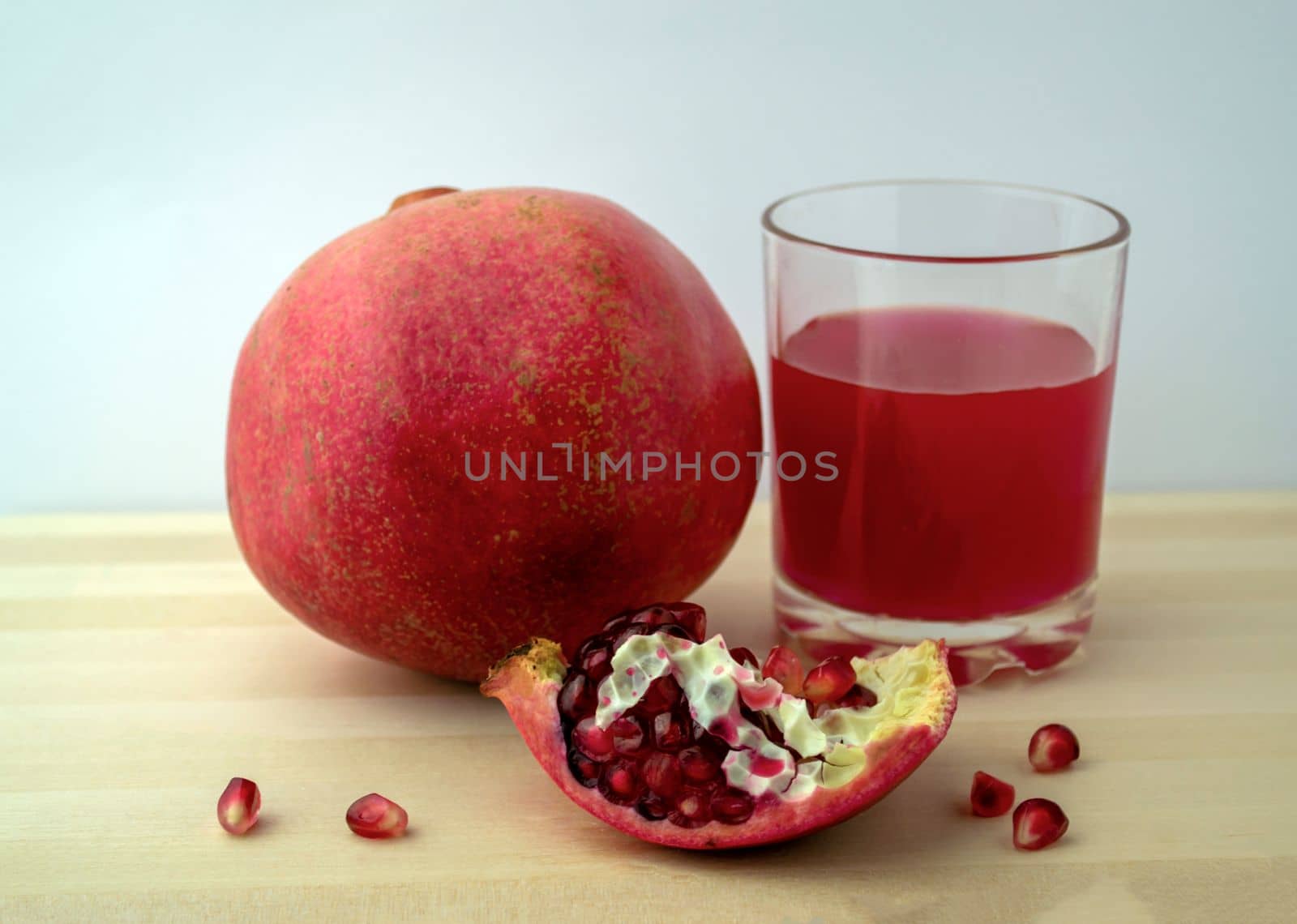 Pomegranate and pomegranate juice, photo. Photo of pomegranate and pomegranate juice in a glass on a wooden table.