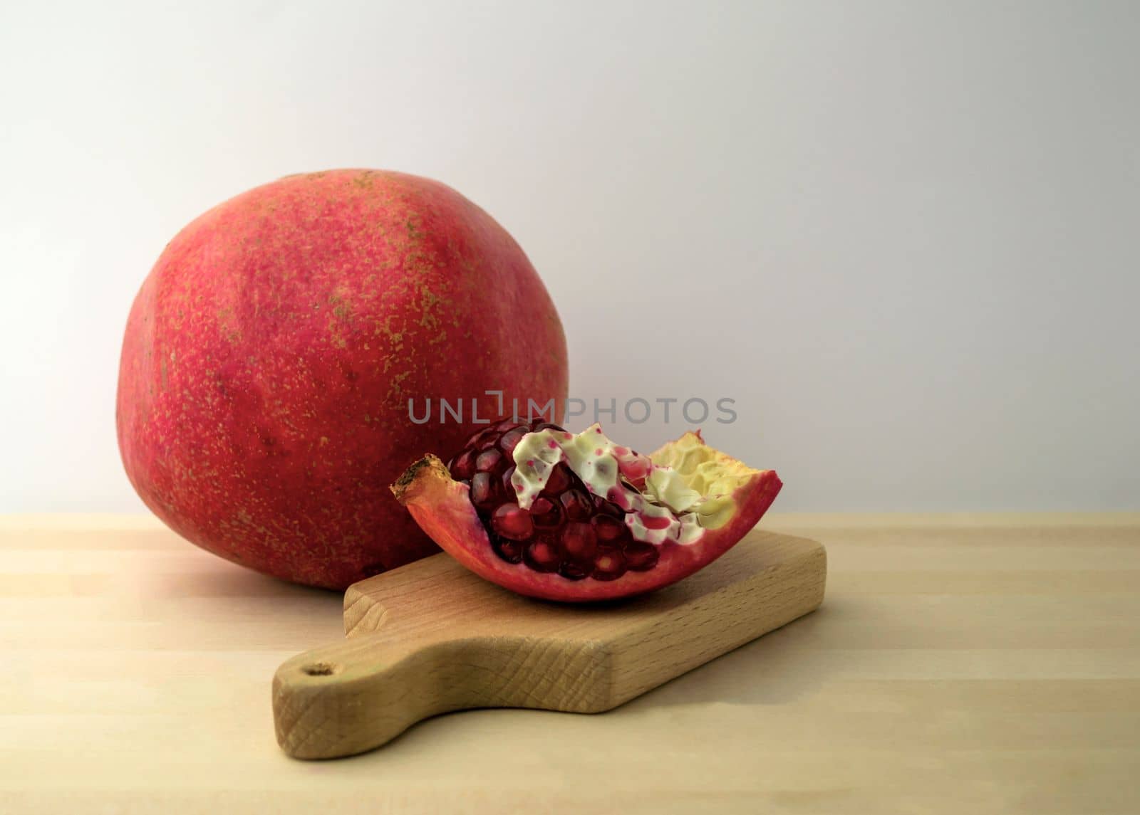 Pomegranate and pomegranate slice, photo. Pomegranate and pomegranate slice on a board on a wooden table.