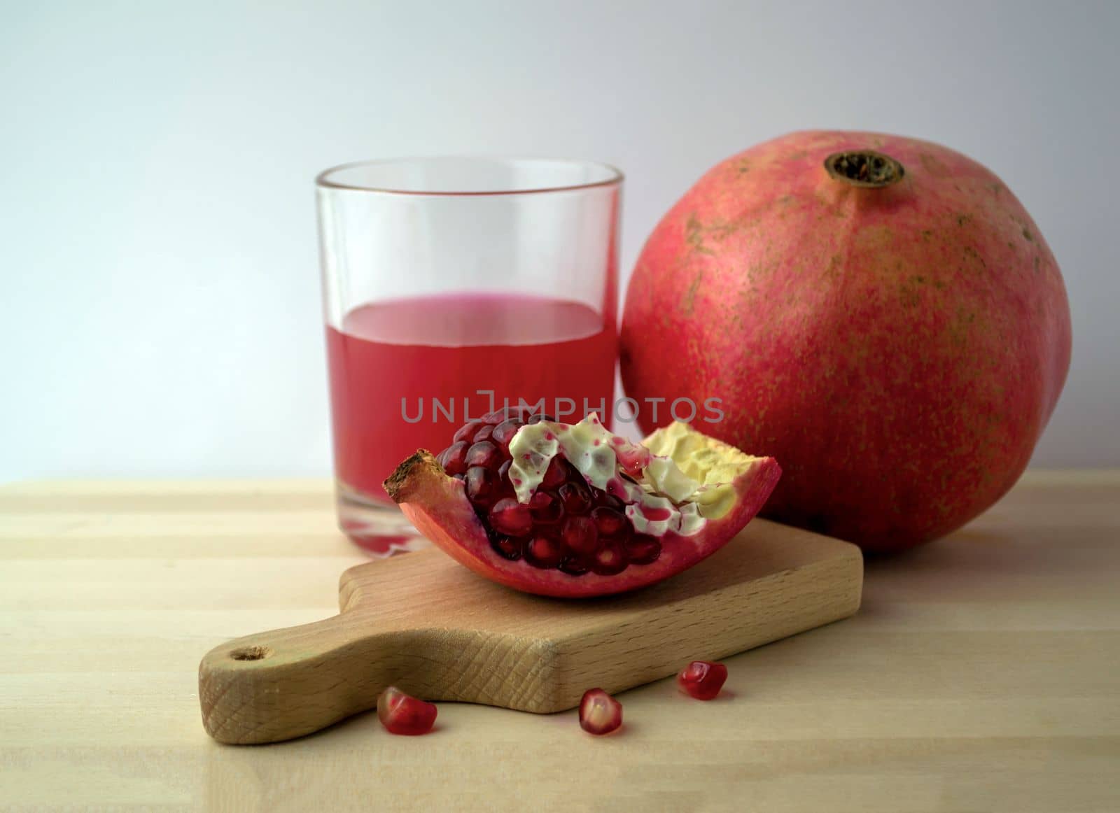 Pomegranate and pomegranate juice, photo. Photo of pomegranate and pomegranate juice in a glass on a wooden table.