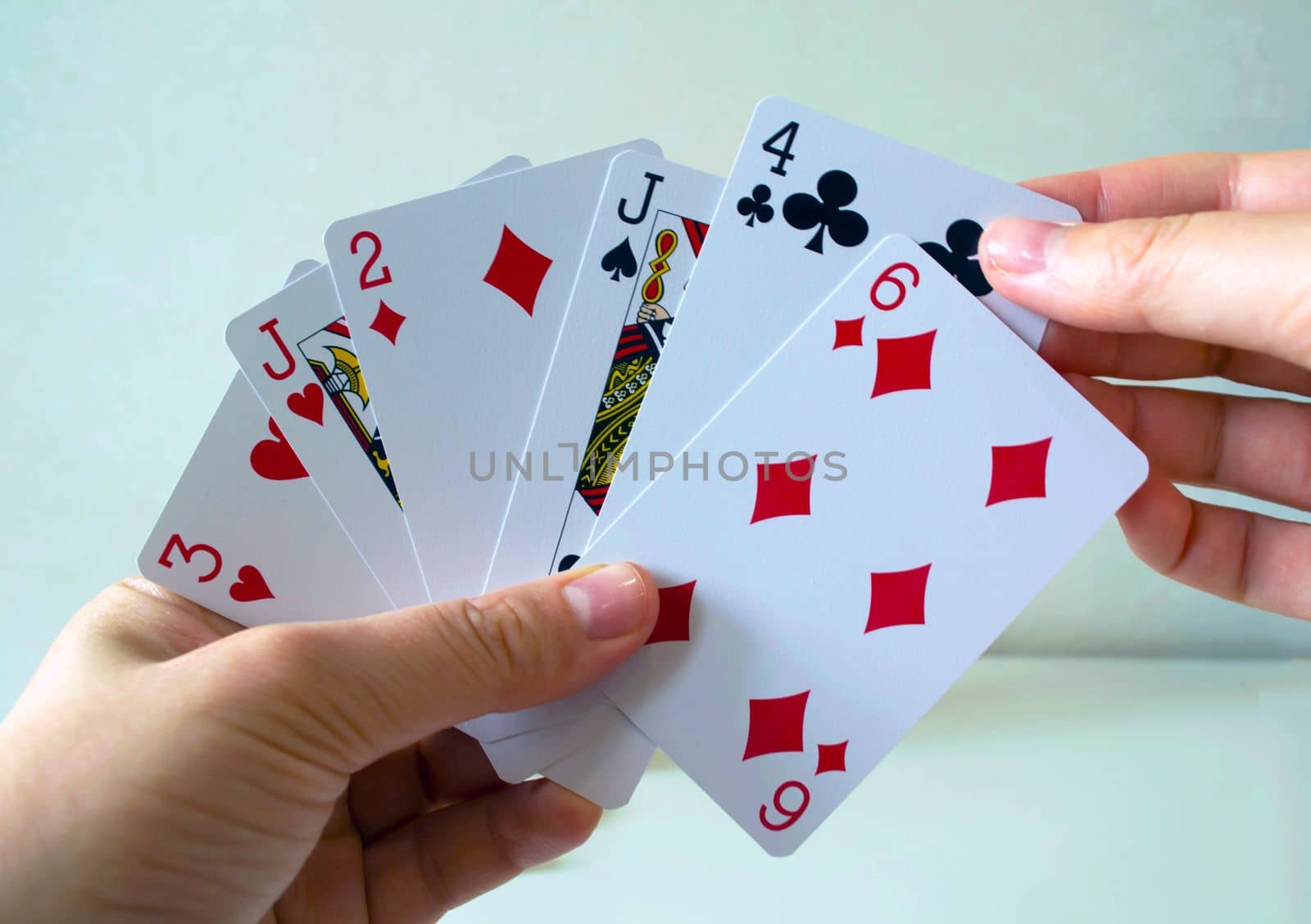 Playing cards. The left hand of the woman holds playing cards, the right hand takes out the card.