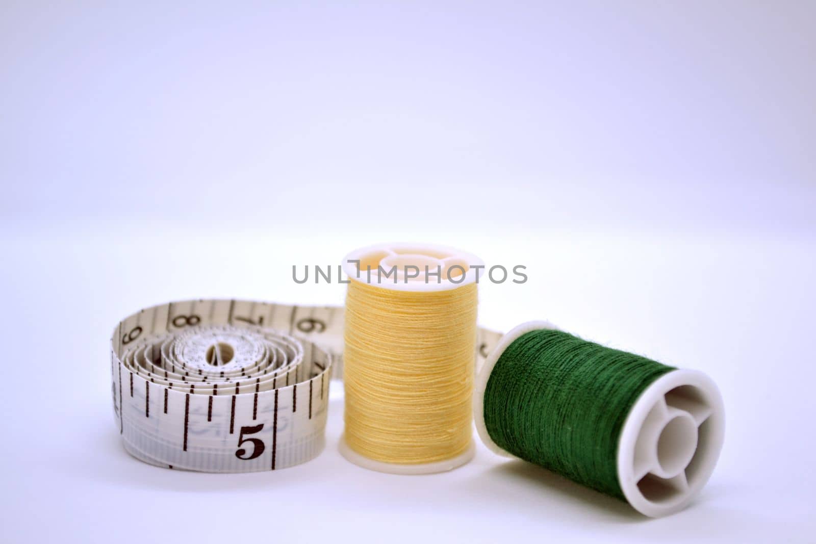 Threads and sewing ruler. In the photo, the threads are yellow and green and a sewing meter.