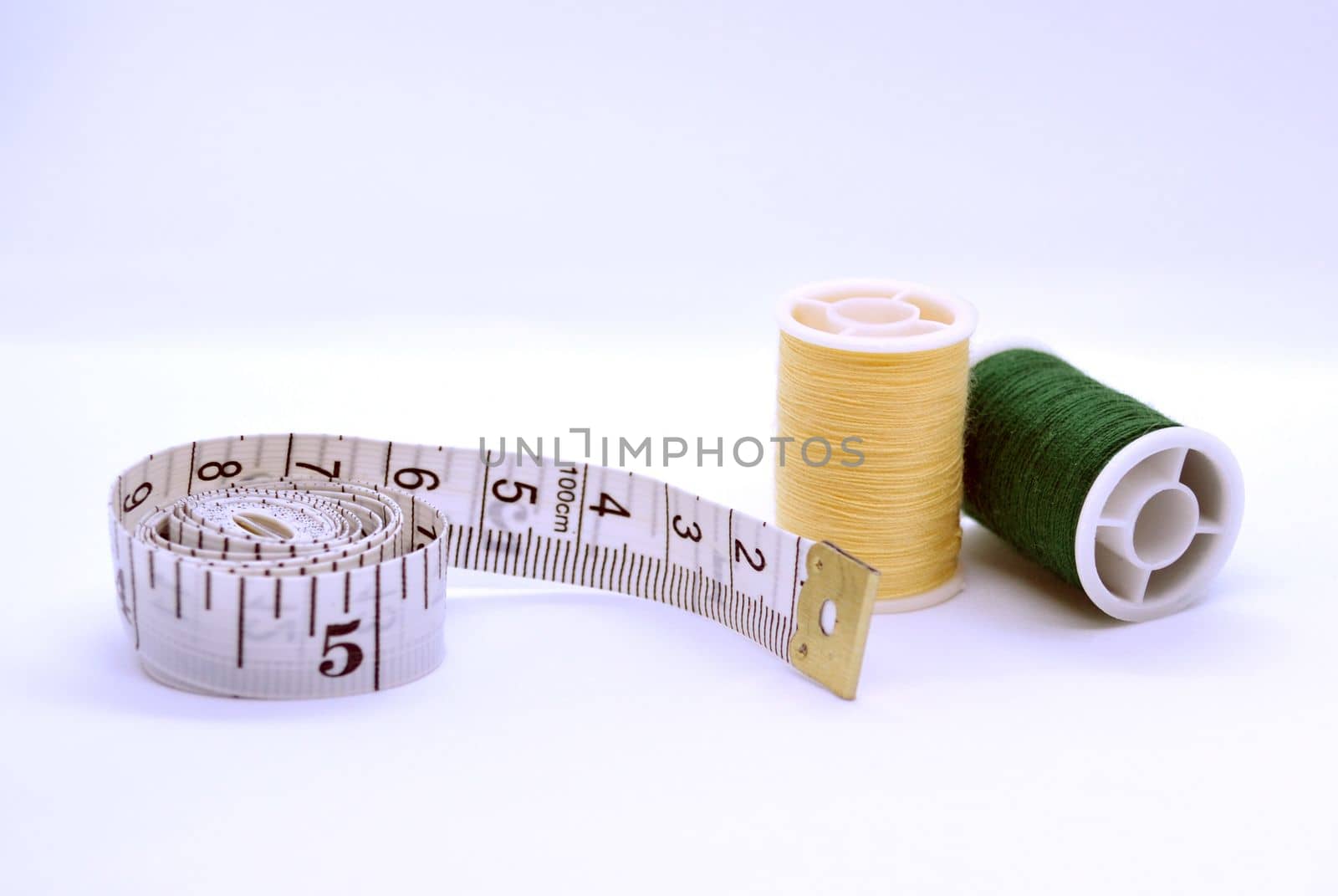 Threads and sewing ruler. In the photo, the threads are yellow and green and a sewing meter.