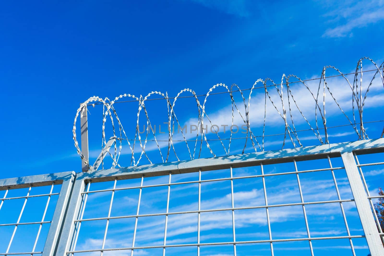 Barbered wire over blue sky and on building ground, rusty