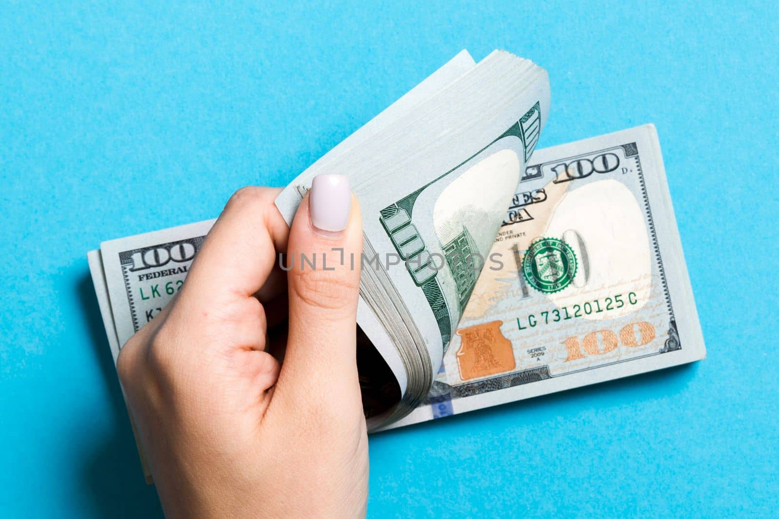 Top view of a businesswoman's hands counting one hundred dollar banknotes on colorful background. Success and wealth concept with copy space.