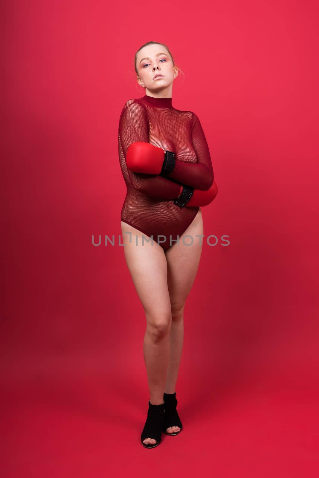 Seductive confident female boxer in gloves studio, sporty woman posing looking at camera.