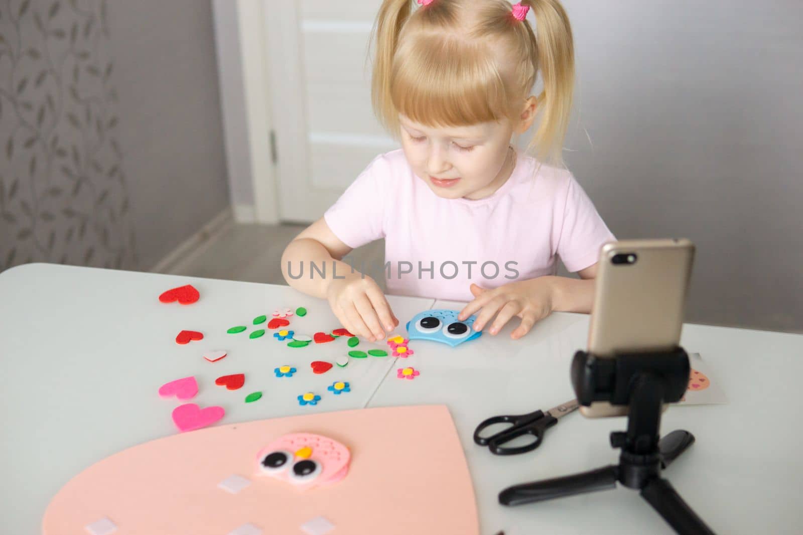 A blogger girl makes a felt craft for Valentine's Day in the shape of a heart. The concept of children's creativity and handmade.