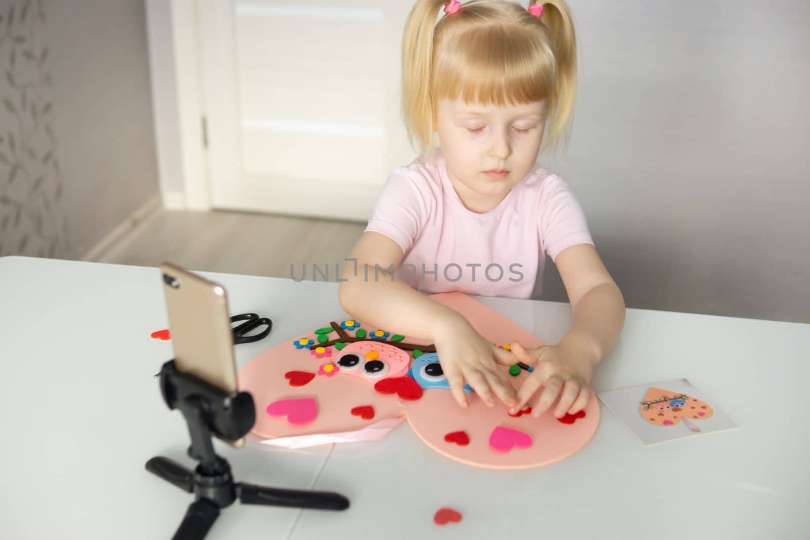 A blogger girl makes a felt craft for Valentine's Day in the shape of a heart. The concept of children's creativity and handmade