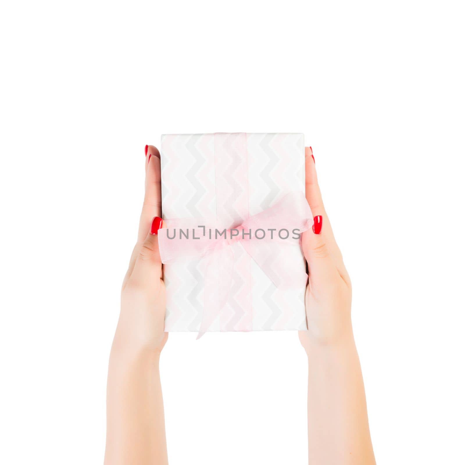 Woman hands give wrapped Christmas or other holiday handmade present in colored paper with pink ribbon. Isolated on white background, top view. thanksgiving Gift box concept.