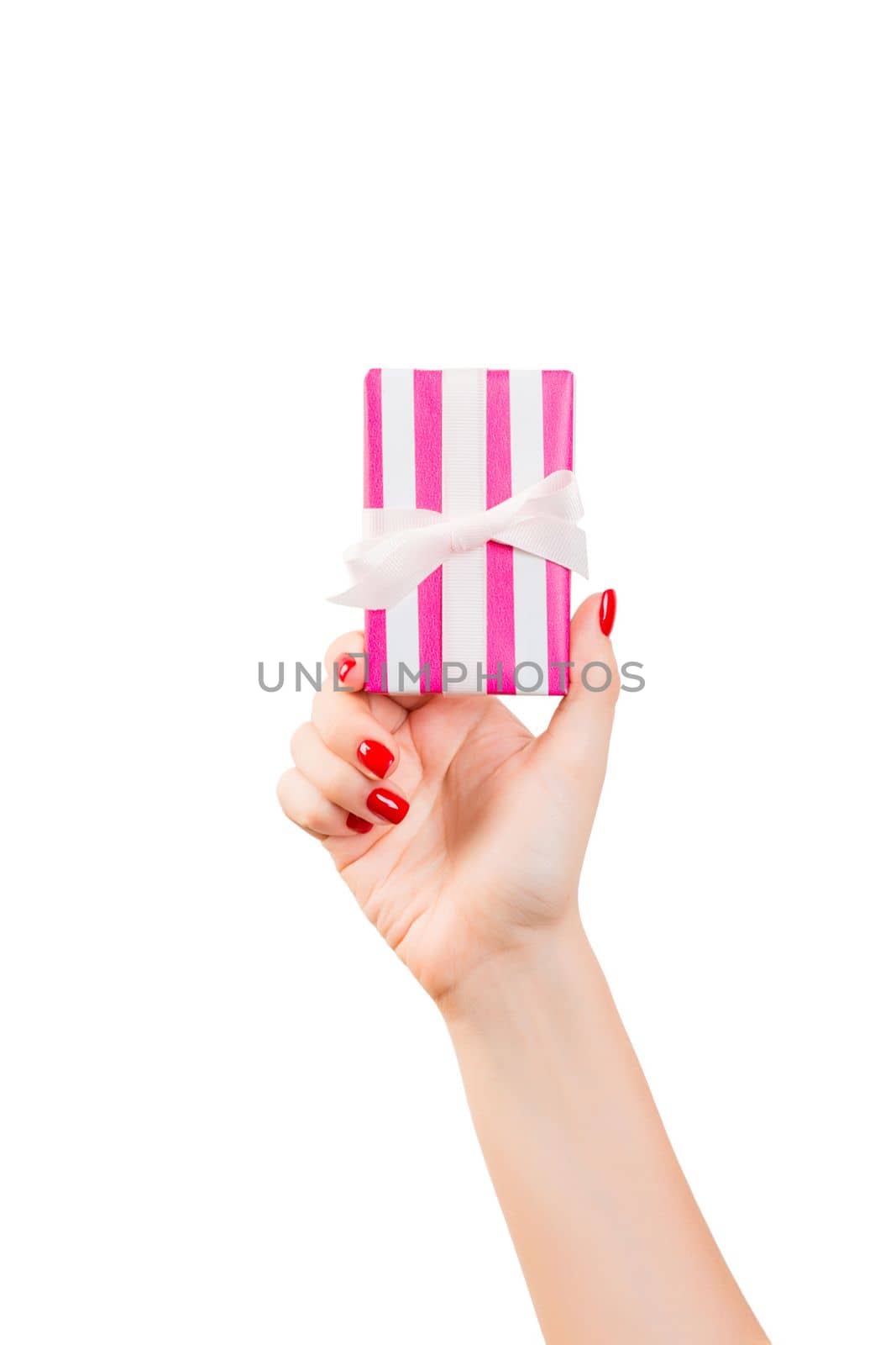 Woman hands give wrapped Christmas or other holiday handmade present in pink paper with white ribbon. Isolated on white background, top view. thanksgiving Gift box concept.