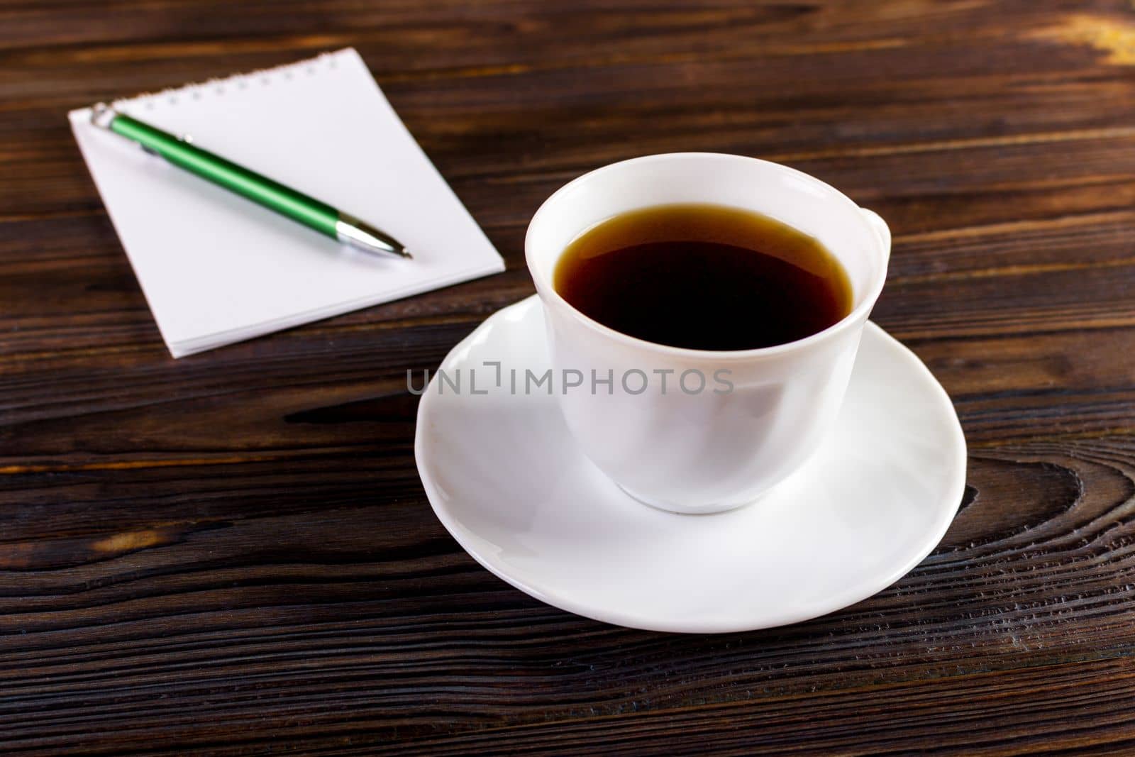 notebook with pen and coffee cup on wooden background, business concept.