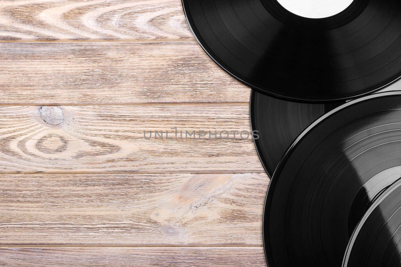 Black vinyl records on the wooden table, selective focus with copy space. Top view